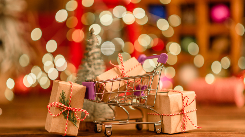 Carrello con regali di Natale su uno sfondo con luci di Natale